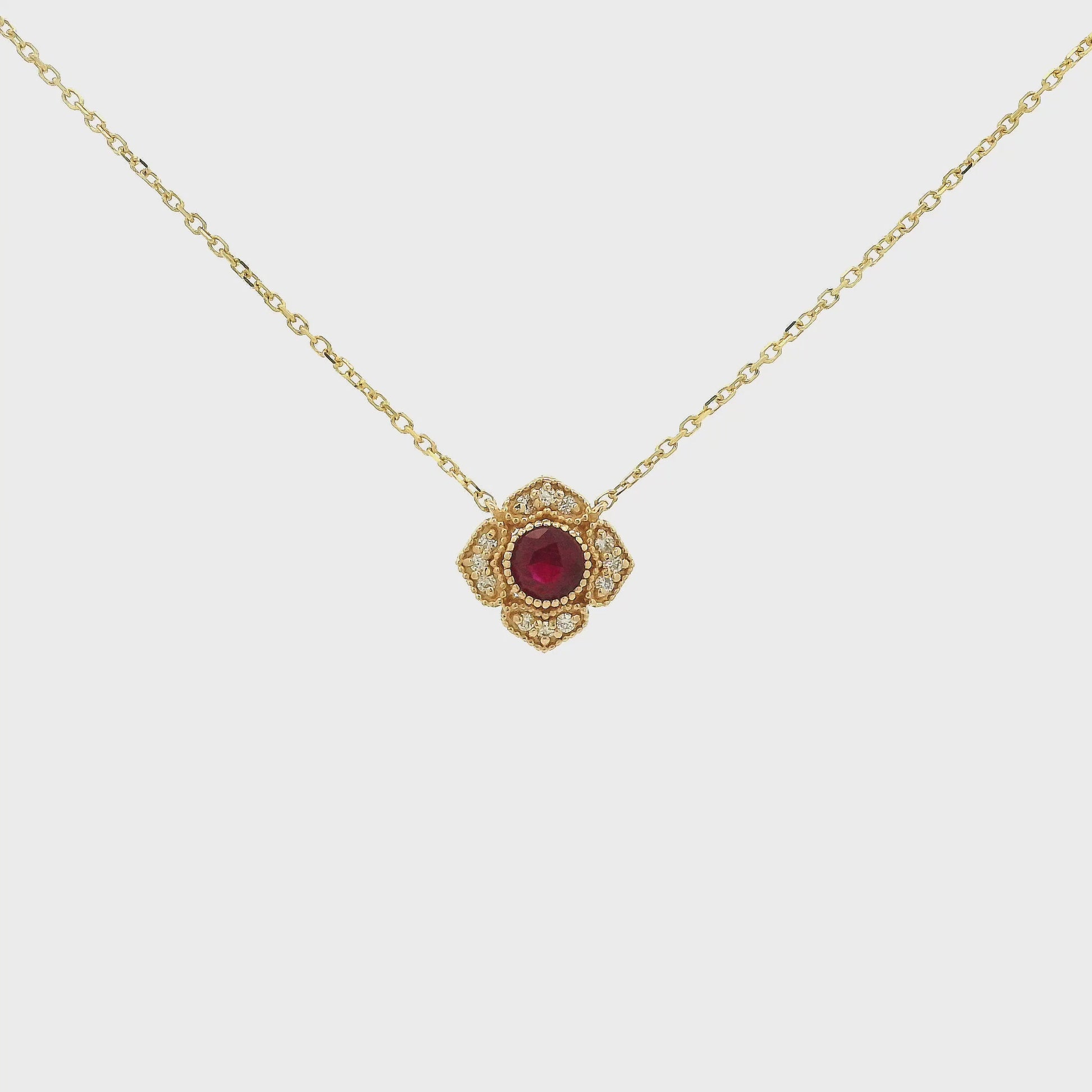 A Yellow Gold Flower Pendant with a milgrain bezel set round cut natural Ruby in the centerand diamonds with a chain attached at Forever Rox Fine Jewelry, Lake Tahoes Best Jewelry Store
