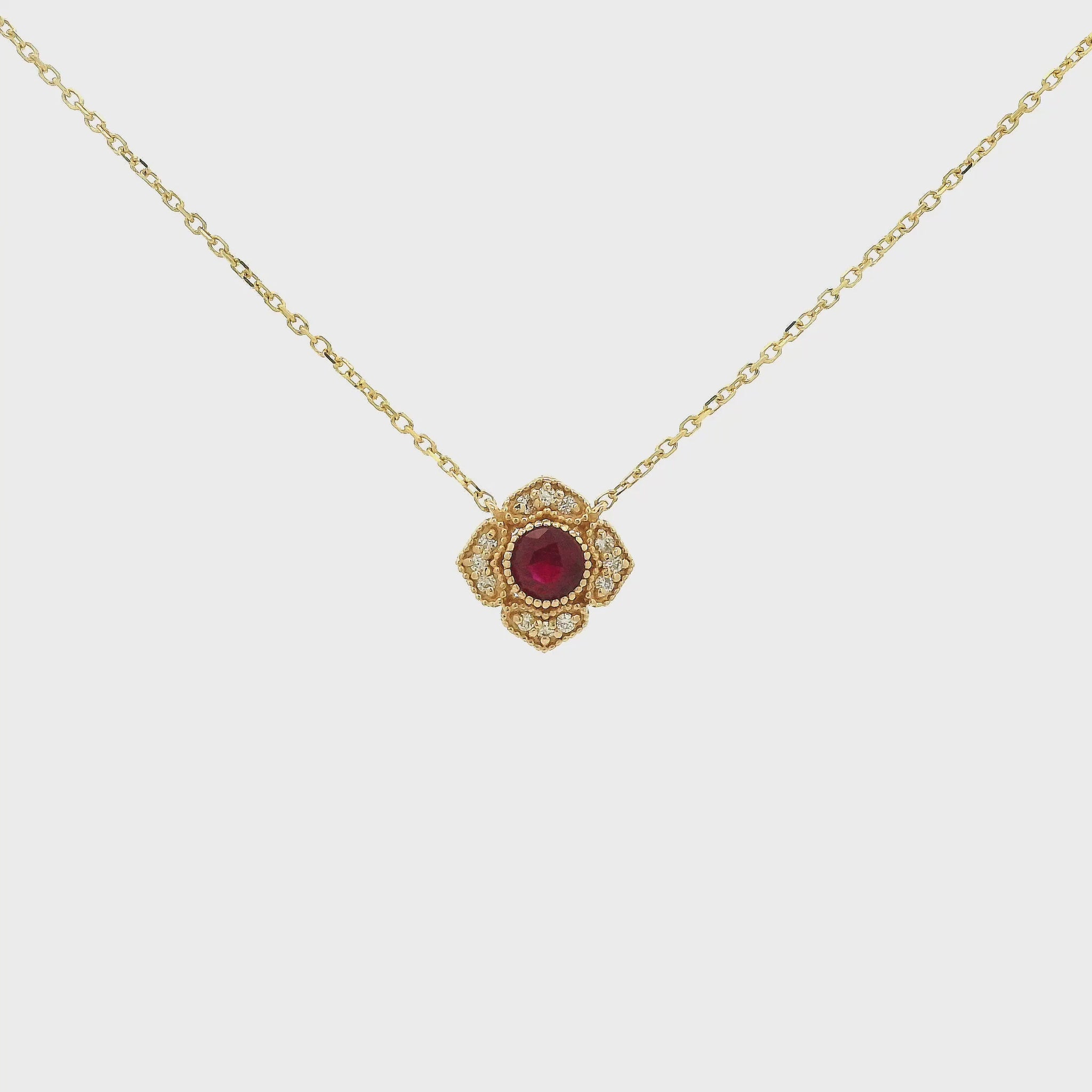 A Yellow Gold Flower Pendant with a milgrain bezel set round cut natural Ruby in the centerand diamonds with a chain attached at Forever Rox Fine Jewelry, Lake Tahoes Best Jewelry Store