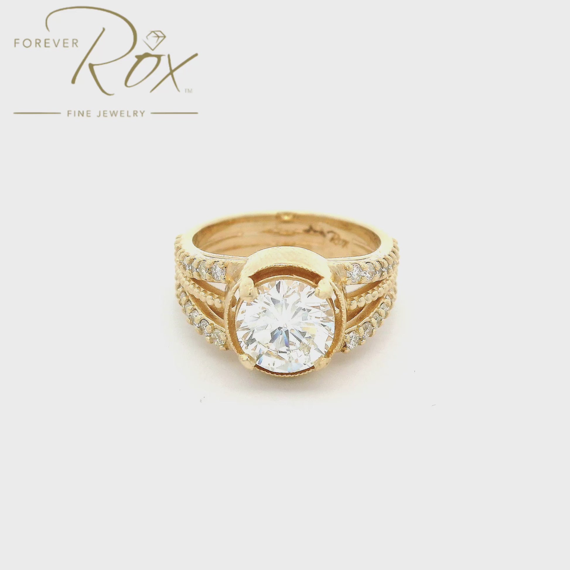 Yellow Gold ring with one center cut round diamond and a shank that splits into three with the outsides having diamonds and the center having a milgrain design at Forever Rox Fine Jewelry