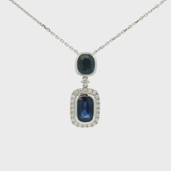 A White Gold Pendant Necklace with two bezel set oval and round cut blue Sapphires in the center with the bottom one having a diamond halo and attached to a diamond by the yard chain at Forever Rox Fine Jewelry, Lake Tahoes Best Jewelry Store