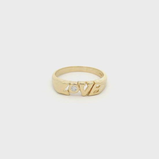 A Yellow Gold Band that says LOVE with a bezel set round cut Dimond in the "o" at Forever Rox Fine Jewelry, Lake Tahoes Best Jewelry Store