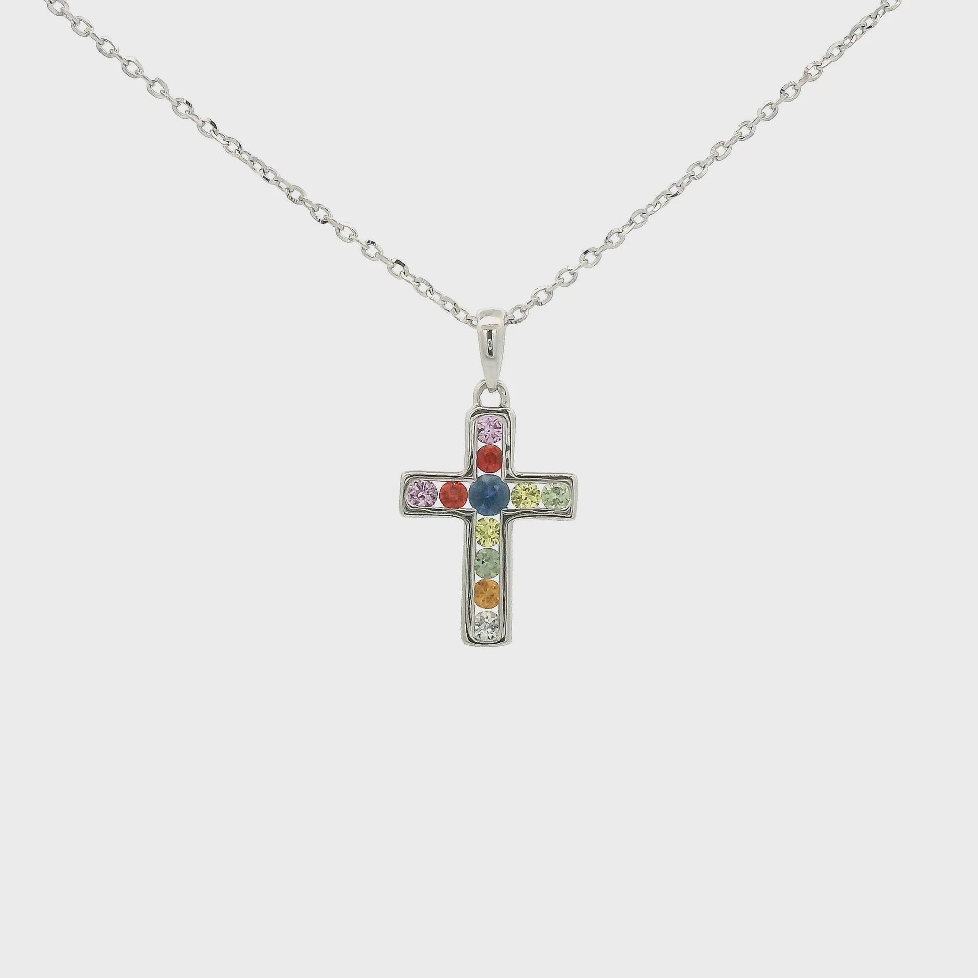 A White Gold Cross Pendant with channel set round cut blue, orange, pink, green and white Sapphires in the center  at Forever Rox Fine Jewelry, Lake Tahoes Best Jewelry Store
