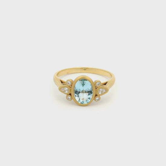 A Yellow Gold Ring with a bezel set oval cut Aquamarine in the center with two round cut and one pear cut diamond on each side - Lake Tahoes  Best Jewelry Store, Forever Rox Fine Jewelry