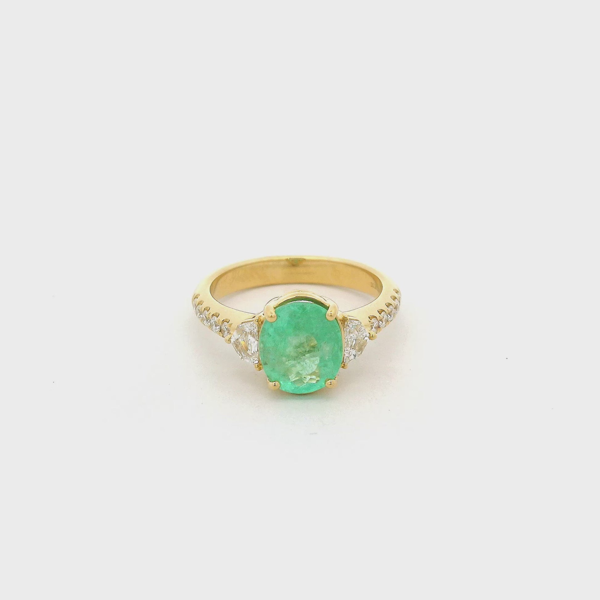A Yellow Gold Ring with a prong set oval cut natural Green Paraíba Tourmaline in the center with two chevron cut diamonds next to it and diamonds down the shank at Forever Rox Fine Jewelry, Lake Tahoes Best Jewelry Store.