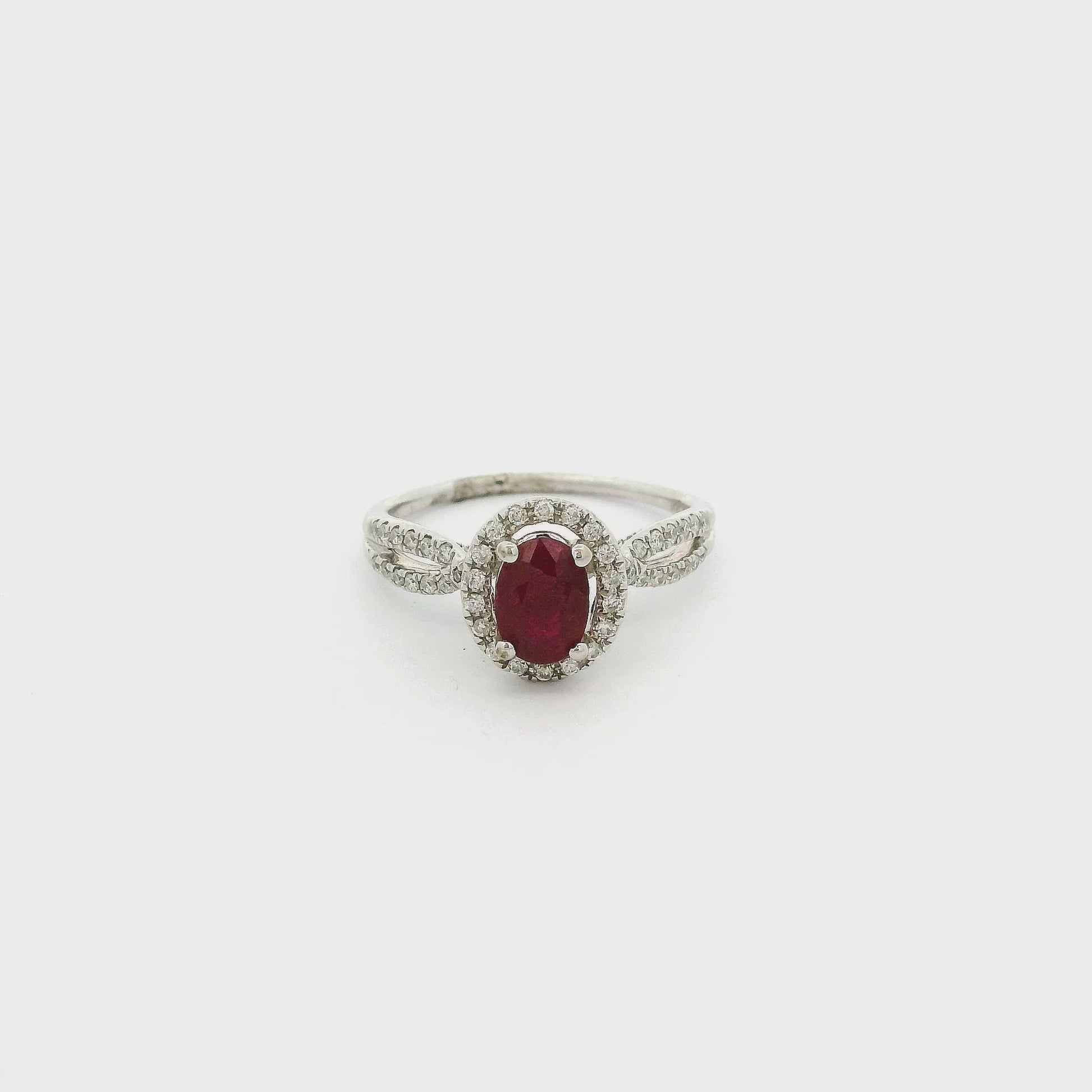 A White Gold Ring with a prong set oval cut natural Ruby in the center with a diamond halo and diamonds down the crossover shank at Forever Rox Fine Jewelry, Lake Tahoes Best Jewelry Store