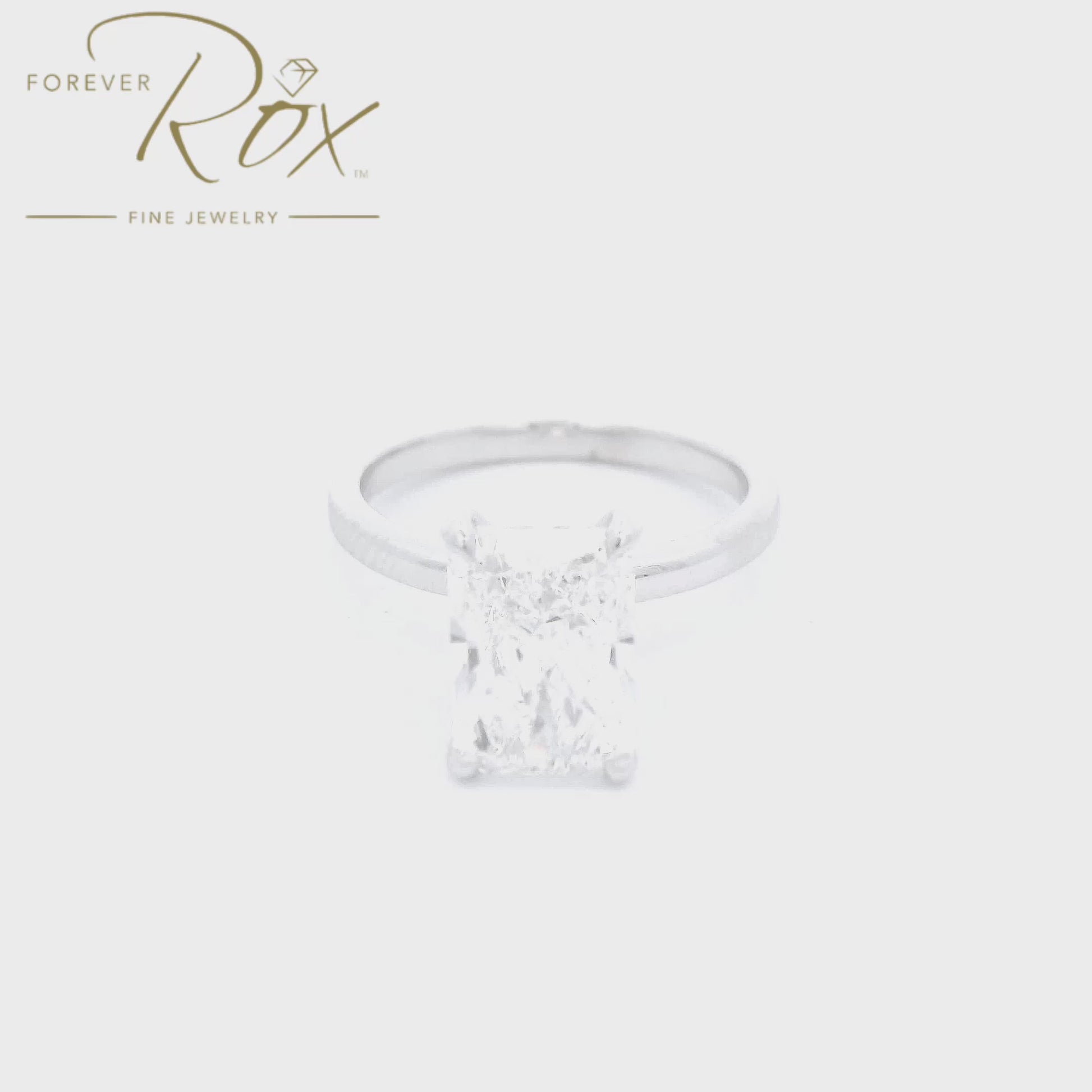 This custom ring features a striking long radiant-cut D color, VS1 clarity diamond, set in sleek 14k white gold. A delicate halo of diamonds surrounds the head below the center stone, creating a clean, modern statement with timeless appeal mad  at Forever Rox Fine Jewelry, Lake Tahoes Best Jewelry Store