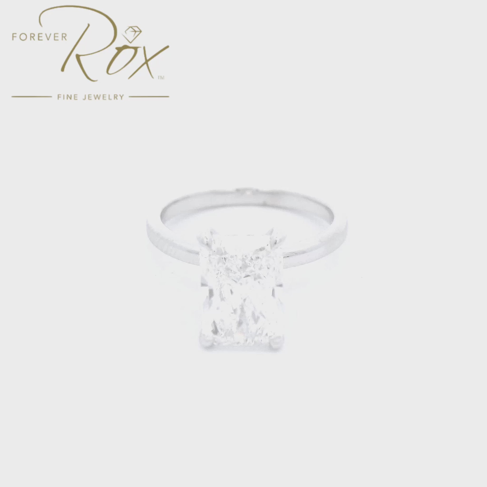 This custom ring features a striking long radiant-cut D color, VS1 clarity diamond, set in sleek 14k white gold. A delicate halo of diamonds surrounds the head below the center stone, creating a clean, modern statement with timeless appeal mad  at Forever Rox Fine Jewelry, Lake Tahoes Best Jewelry Store