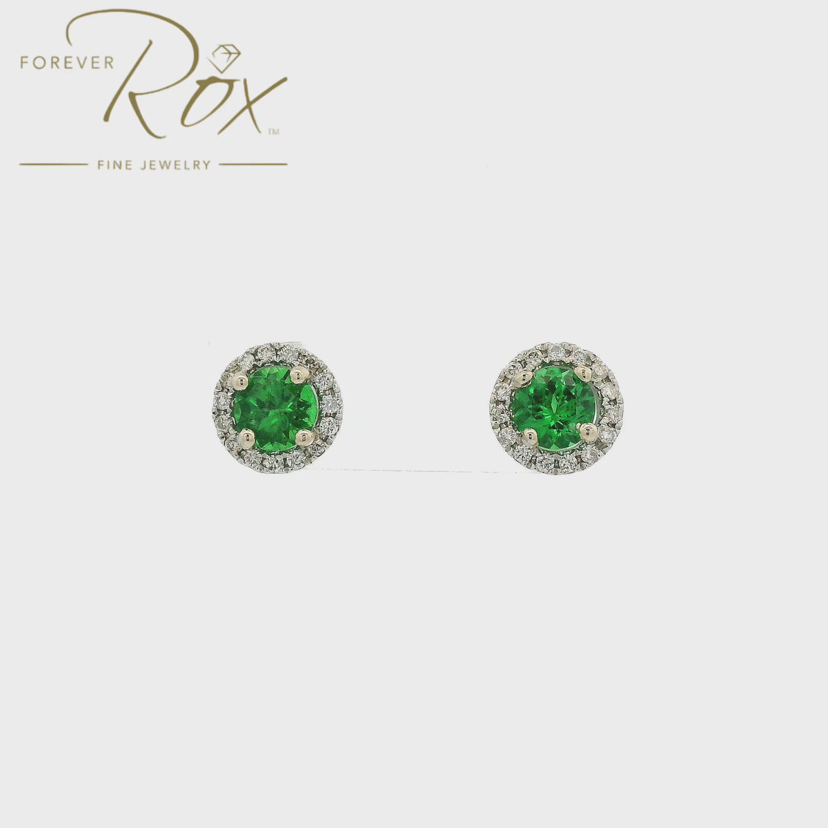 A Pair of White Gold Stud Earrings with prong set round cut natural Tsavorite Garnets in the center with a diamond halo at Forever Rox Fine Jewelry, Lake Tahoes Best Jewelry Store